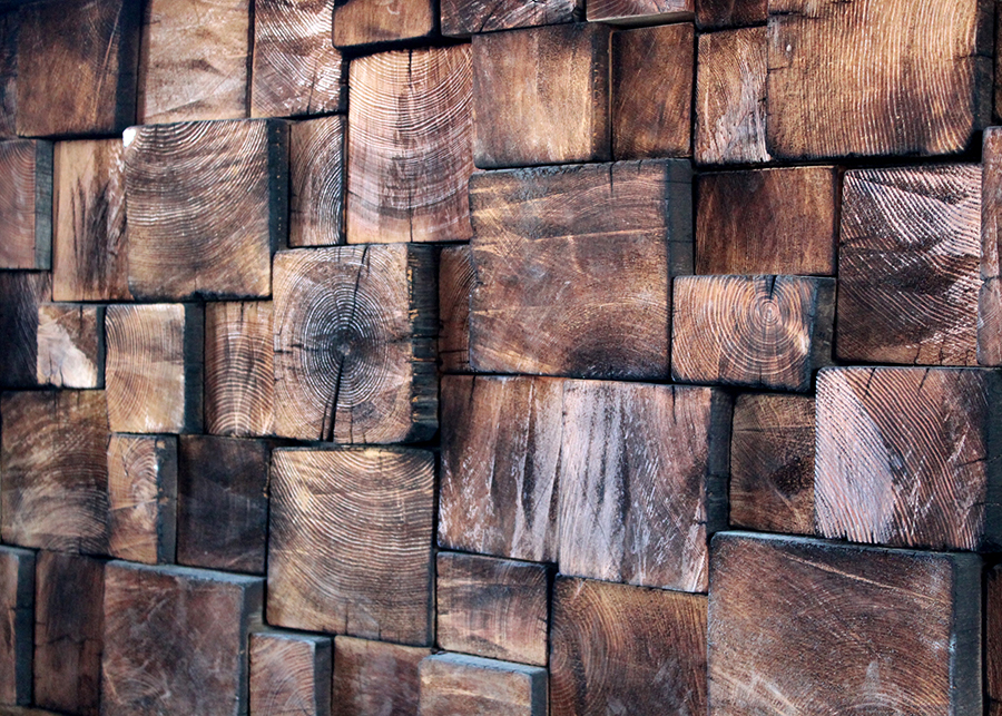 A close up of the reclaimed wood used to create the front of the taphouse’s custom bar made of dark rough-cut wooden blocks 
